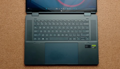Laptop computer opened flat on cork surface showing desktop with circular design on screen.