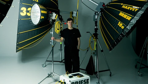 Professional film production lighting setup with large parabolic reflectors and a cinematographer in a controlled studio environment.