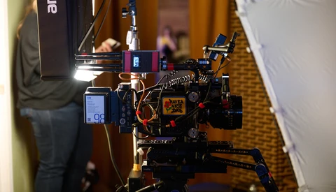 Professional cinema camera rig with mounted monitors, lighting, and support equipment on a carpeted floor.