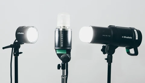 Three studio flash units mounted on stands against a white background.