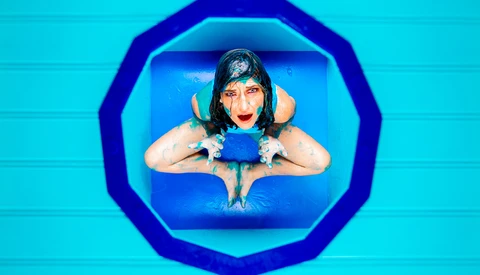 Person in blue swimming attire viewed from above through a circular frame in a swimming pool.