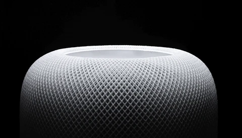 Close-up of a spherical speaker with a mesh fabric surface texture against a dark background.