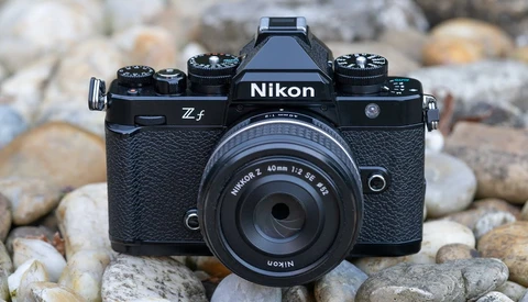 Nikon Z f mirrorless camera with 40mm f/2 lens on rocky ground backdrop.