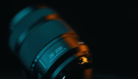 Close-up of a telephoto lens with 28-200mm focal length marking visible against dark background.