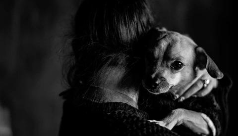 Person holding a small dog over their shoulder in a high-contrast black and white portrait.