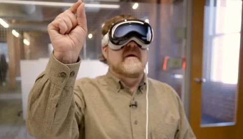 Man wearing VR headset with fist raised indoors.
