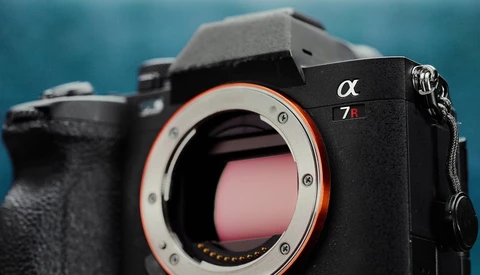 Sony α7R mirrorless camera body with open shutter, showing red sensor contacts against blue background.