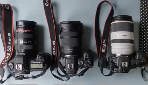 Three Canon EOS DSLR cameras with different lenses mounted, displayed side by side with red straps against a white background.