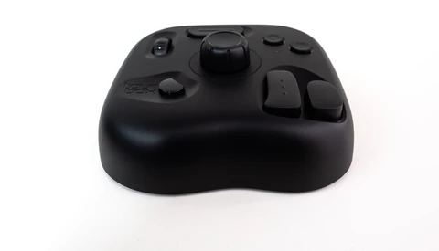 Black wireless game controller with rounded body and multiple buttons against white background.
