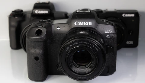 Canon EOS R5 mirrorless camera with RF 50mm lens in front of other Canon camera bodies.