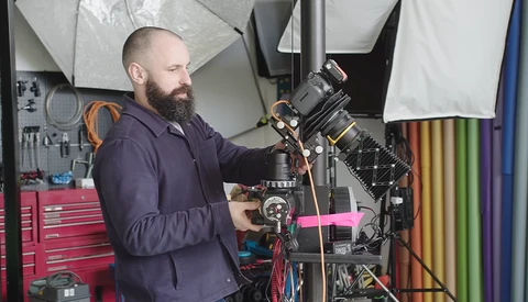 Cinematographer operating a professional cinema camera mounted on a rig in a studio setup.