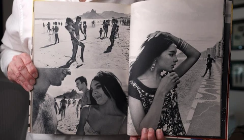 Open photography book displaying black and white beach portraits and candid shots across two pages.