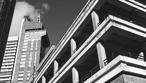 Black and white photograph of modern skyscrapers shot from below, emphasizing geometric lines and architectural contrast.
