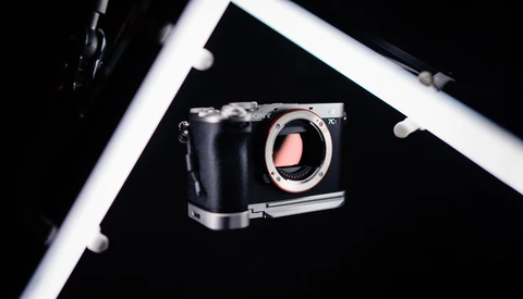 Mirrorless camera body with open shutter displayed against black background with white frame border.