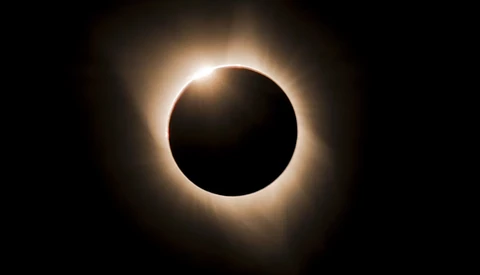 Total solar eclipse with the moon blocking the sun's disk and the solar corona glowing brightly around it against a dark sky.