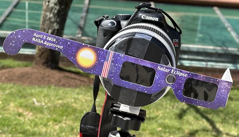 Canon DSLR camera with NASA-approved solar eclipse glasses mounted in front of the lens.