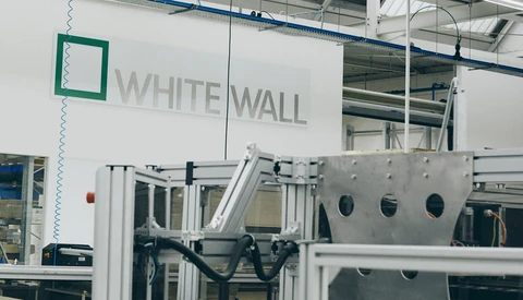 Industrial manufacturing facility with White Wall branding visible on white wall signage above machinery.