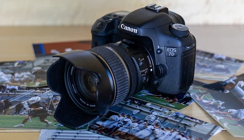 Canon EOS DSLR camera with attached lens resting on printed photographs.