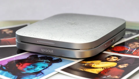 Sprocket portable photo printer positioned on colorful printed photographs.