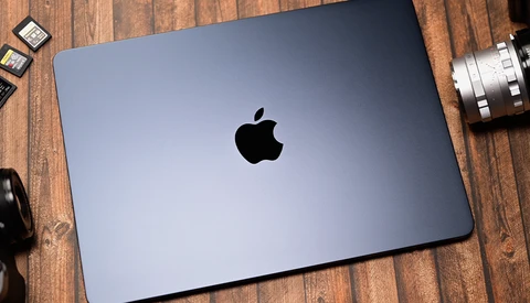 MacBook Pro laptop with closed lid displaying Apple logo on wooden surface surrounded by camera equipment.