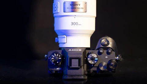 Sony α5000 mirrorless camera with 300mm lens mounted, photographed against dark background with dramatic blue-tinted lighting.