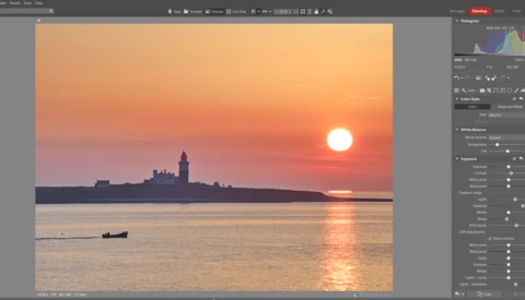 Sunset over water with silhouetted cityscape and small boat in foreground.