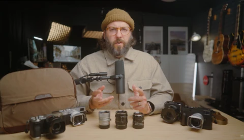 Photographer demonstrating vintage camera lenses arranged on a table during a studio discussion.