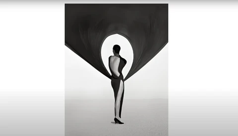Silhouetted figure holding billowing black fabric against a bright backdrop.