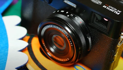 Vintage Minolta camera lens with orange and black detailing mounted on camera body.