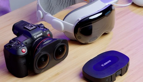 Canon RF mirrorless cinema camera with dual lenses displayed on wooden surface alongside accessories.