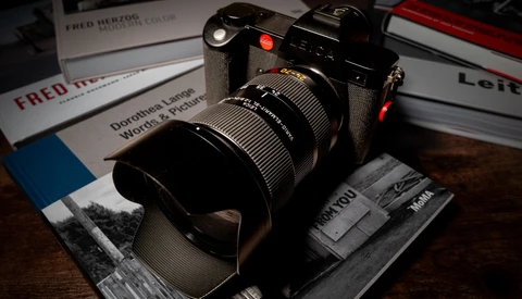 Leica SL2-S mirrorless camera with telephoto lens mounted on photography book.