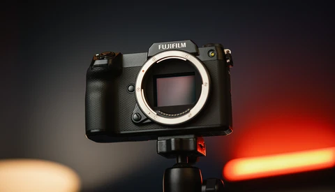 Fujifilm medium format camera body mounted on tripod with warm and cool studio lighting in background.