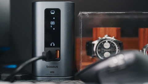 Baseus power strip with touch controls and orange digital watches displayed in background.