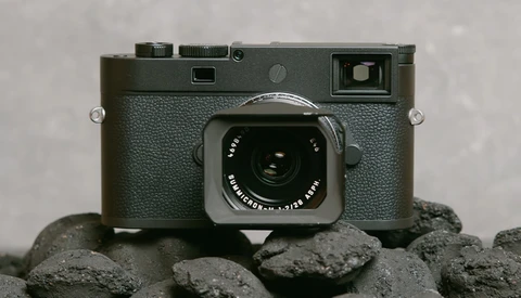 Leica M rangefinder camera with gray textured body and chrome lens, positioned on rough gray stones.