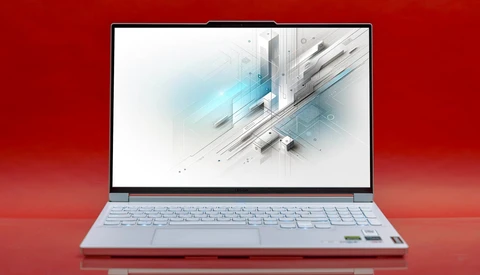 Silver laptop displaying abstract geometric 3D design with blue light streaks on red background.