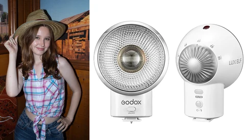 Woman wearing plaid shirt and straw hat posing indoors next to two white LED light fixtures.