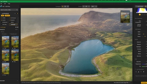 Aerial landscape showing a bright blue lake surrounded by green valleys and brown mountains under golden hour light.
