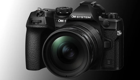 OM System OM-1 mirrorless camera with attached lens, front three-quarter view against neutral background.