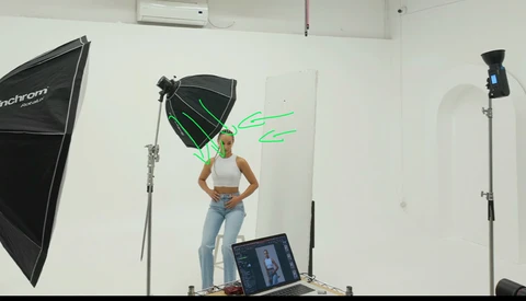 Studio portrait setup with model posing under softbox lighting and green neon sign graphic.