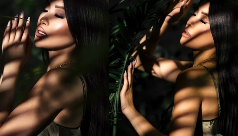 Woman with long black hair posing among tropical foliage with dappled sunlight and shadows across her face and shoulders.