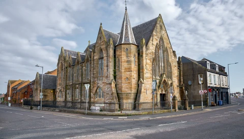 Stone Victorian-era church with Gothic spires at a street corner intersection.