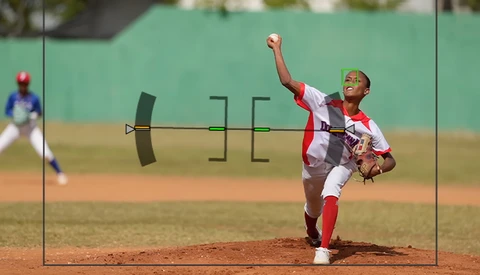 Young baseball pitcher mid-delivery wearing red and white uniform on dirt mound.