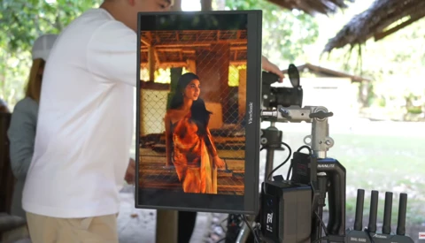 Cinematographer monitoring footage on external monitor during outdoor film production.