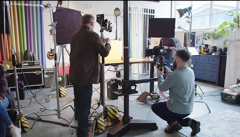 Professional photography studio setup with crew operating camera equipment and lighting rigs during a production shoot.