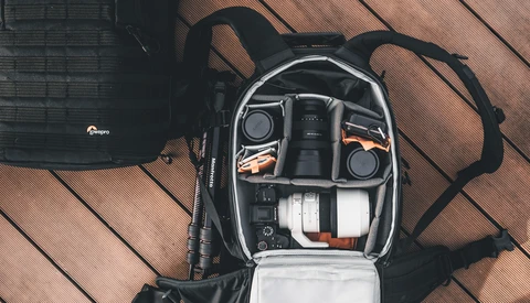 Camera backpack interior with organized gear compartments showing lenses, camera body, and accessories.