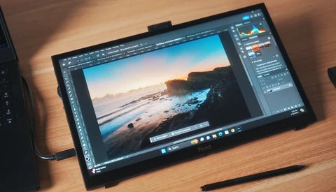 Screenshot of Photoshop displaying a coastal landscape photograph with adjustment panels open on a portable display tablet.