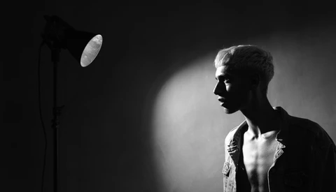Male subject in profile against dark background, illuminated by studio lighting from the left side.