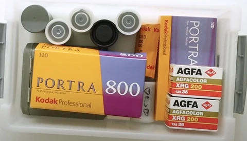 Collection of film photography stock including Kodak Portra 800, Portra 400, and Agfa color film rolls with plastic canisters.