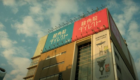 Modern building with red and yellow roofline signage against blue sky with white clouds.