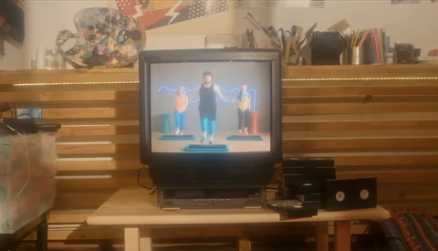 CRT television displaying three people standing on a blue platform against a blue background.